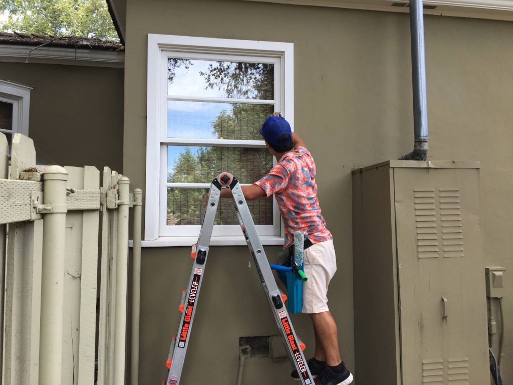 Big Wave Window technician window cleaning on a ladder