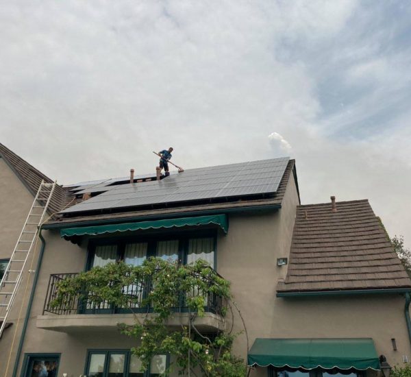 A Big Wave Window service technician solar panel cleaning on a roof