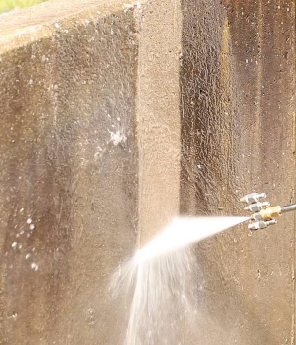 A closeup of pressure washing being performed on a flat concrete surface